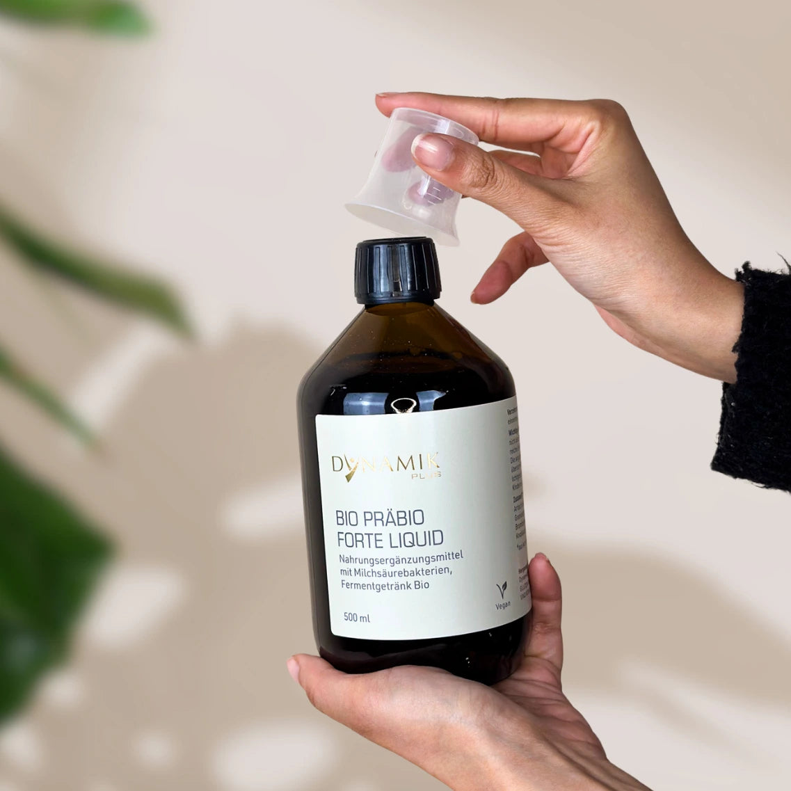 Brauner Glasbehälter mit DYNAMIKPLUS Etikett "Bio Präbio Forte Liquid" und Messbecher als Deckel
