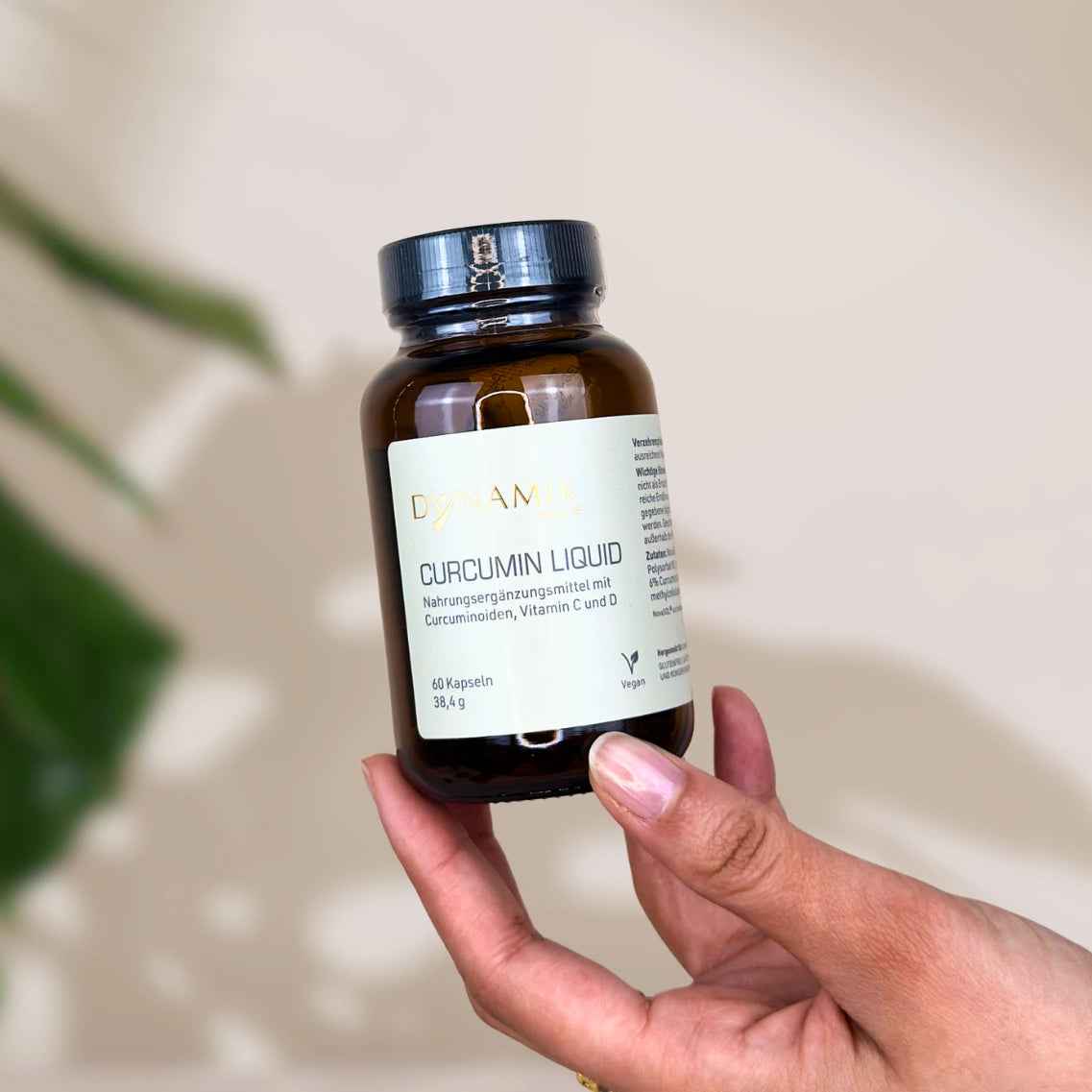 Brauner Glasbehälter mit DynamikPlus "Curcumin Liquid" Etikett und schwarzem Drehverschluss
