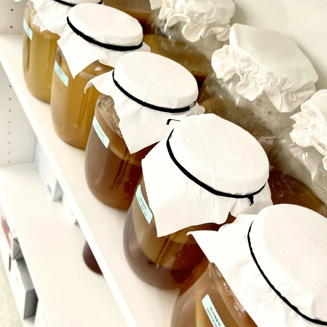 Glasbehälter mit Flüssigkeit aus fermentierten Brokkoli, Beeren und Topinambur