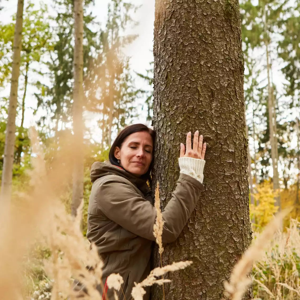 Frau umarmt Baum im Wald