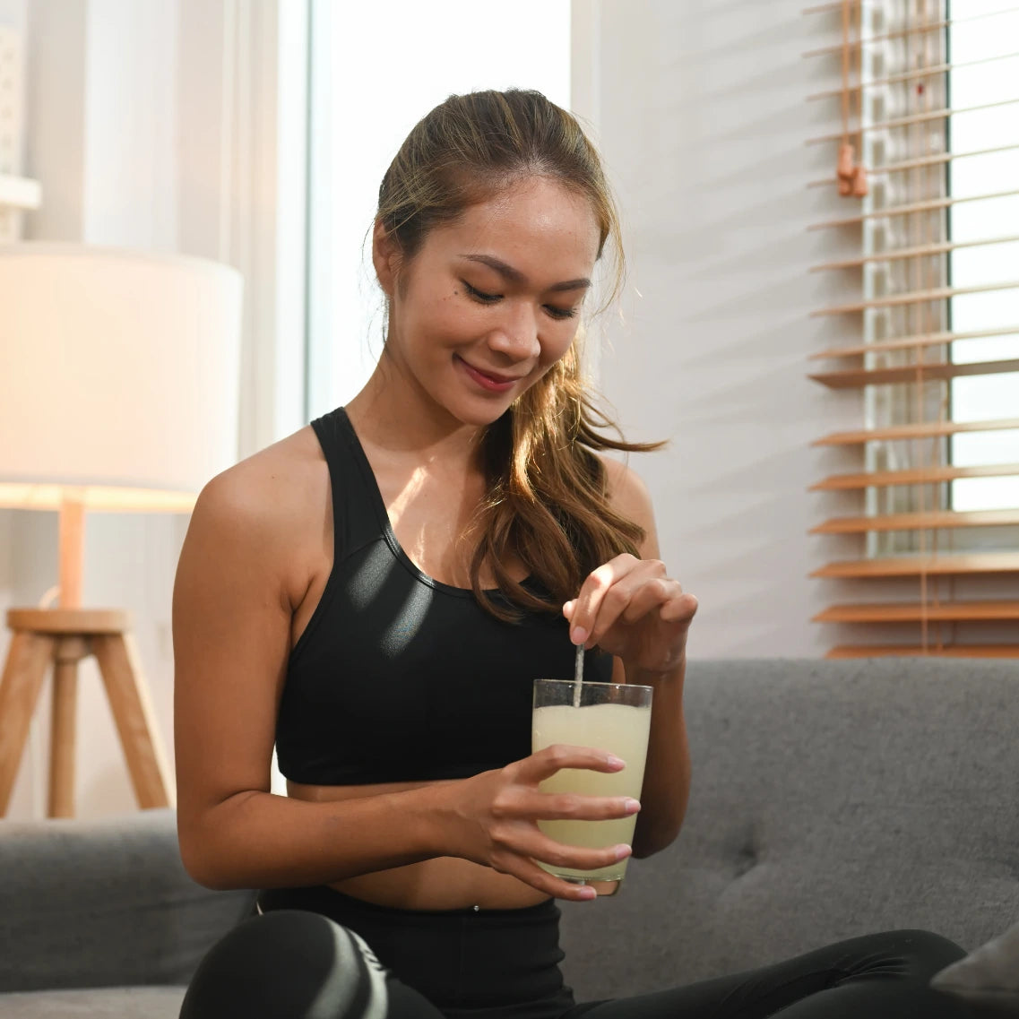 Frau welche sich einen Shake zubereitet auf dem Sofa