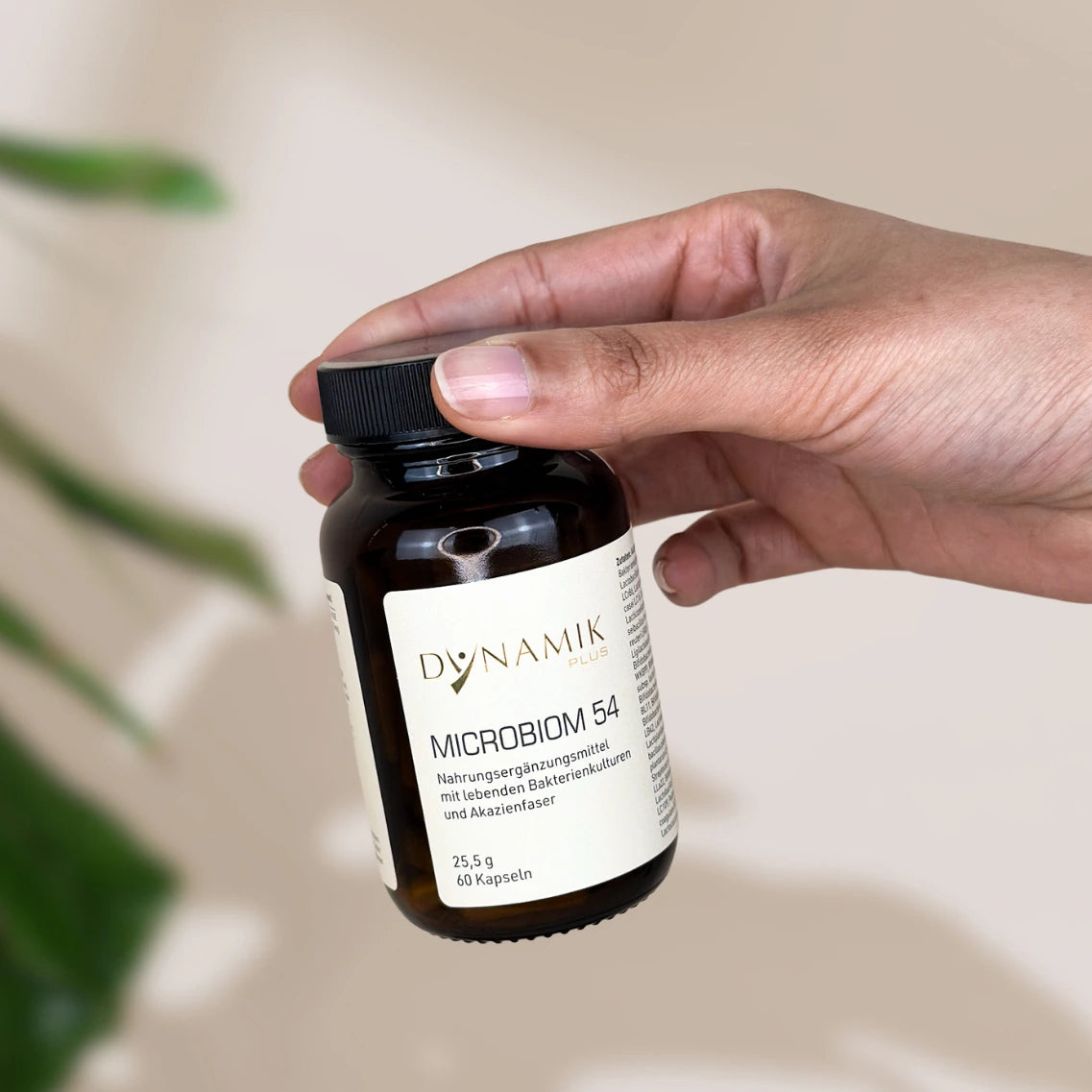 Brauner Glasbehälter mit DYNAMIKPLUS Etikett "Microbiom 54" gehalten von einer Hand