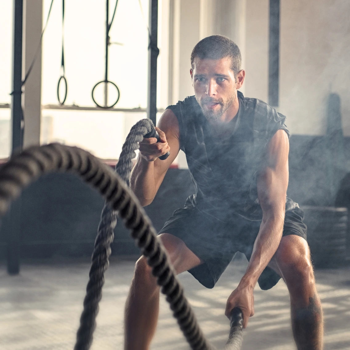 Mann im Fitnessstudio trainierend mit Seilen