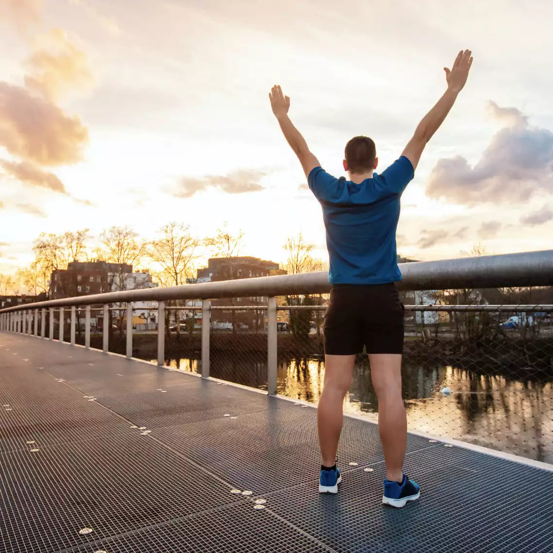 Jubelnder Mann auf Brücke in Sportklamotten