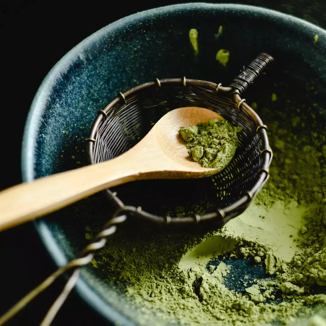gehäufter Matcha Löffel mit Matcha Sieb in blauer Schale