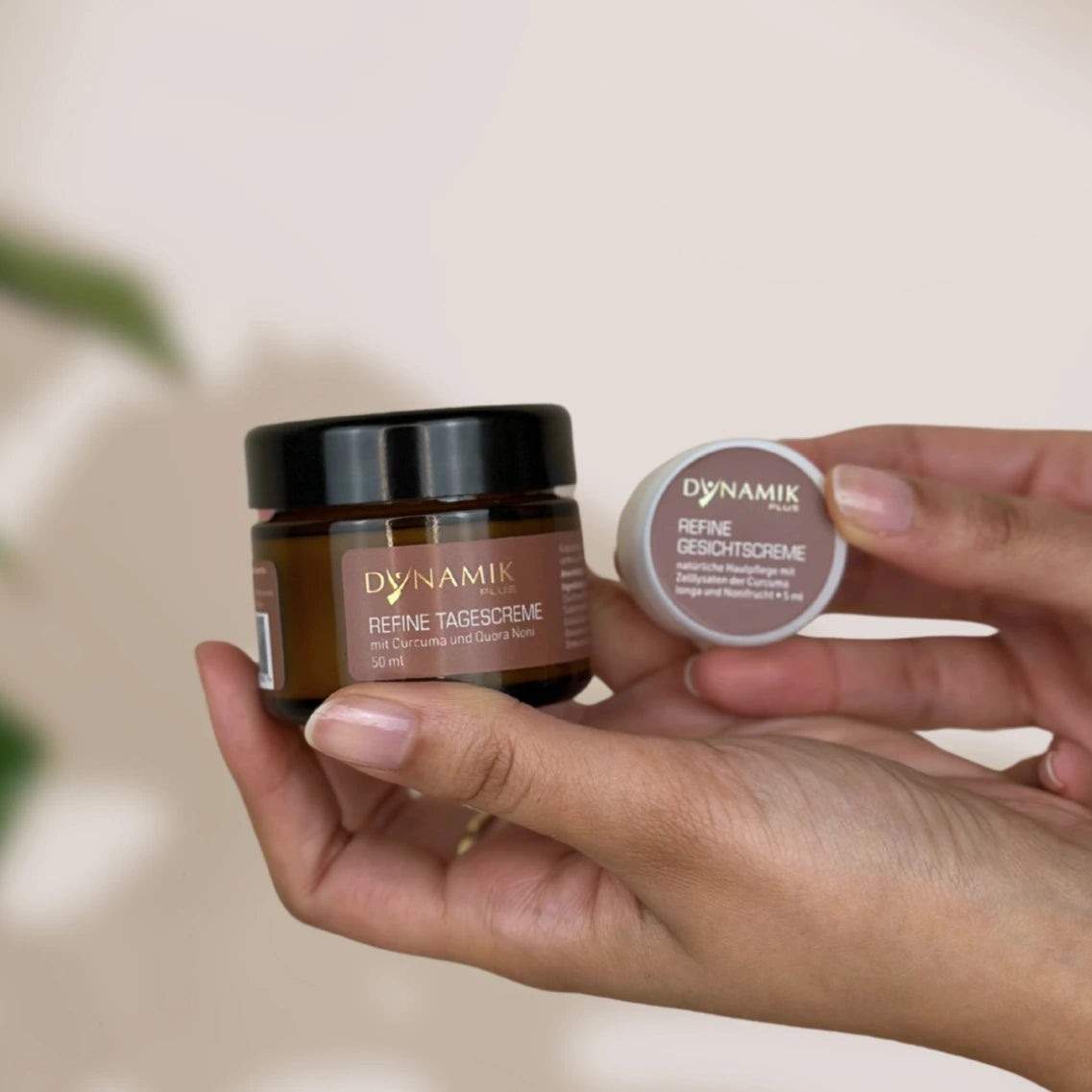 Kleiner runder weißer Plastikbehälter und braunes größeres Glasbehältnis mit jeweils DynamikPlus "Refine Tagescreme" Etikett