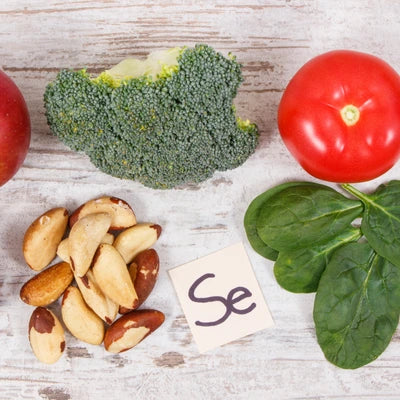 Brokkoli, Tomate, Spinat und Nüsse auf Holz mit einem Schild "Se"
