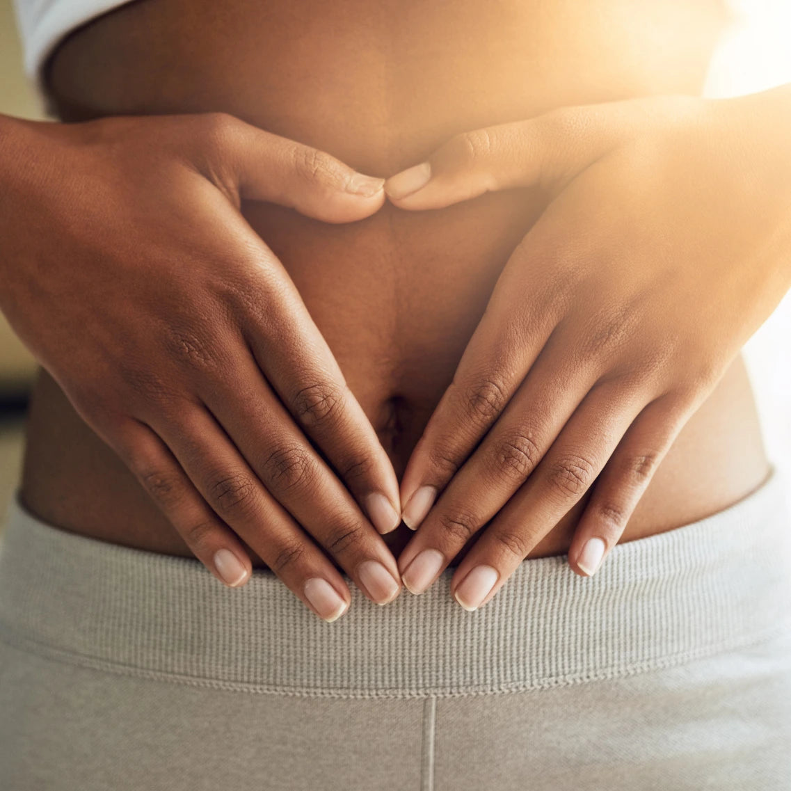 Frau welche sich mit beiden Händen den Bauch hält