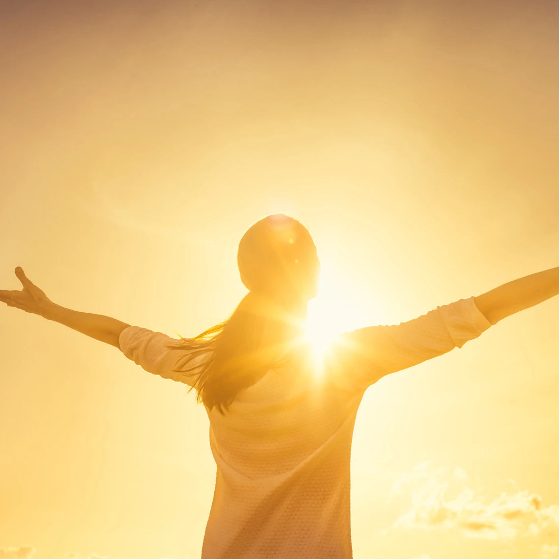 Arme ausstreckende Frau die sich der Sonne zuwendet