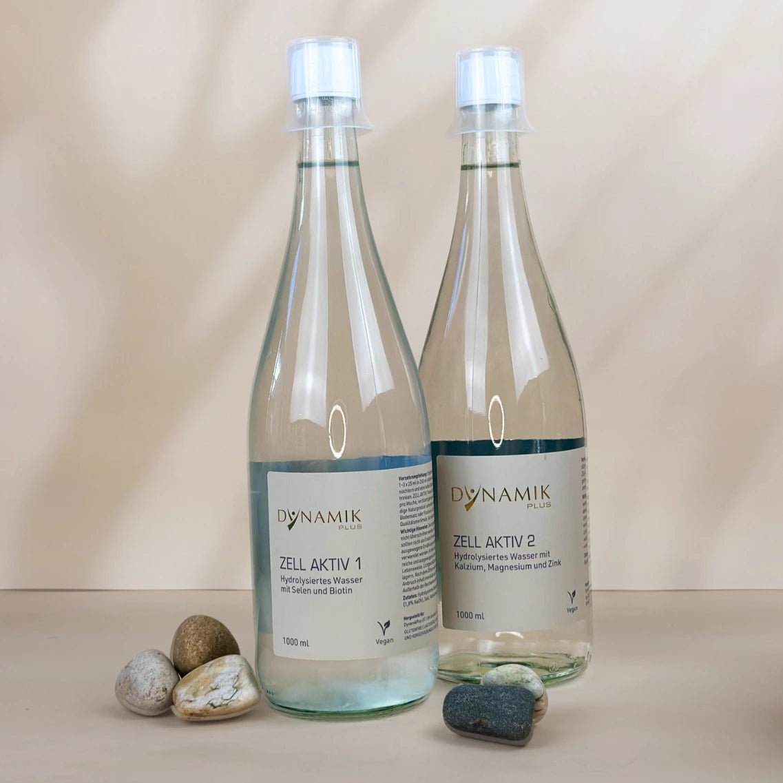 Zwei Glasflaschen mit weißem Deckel, kleinem Messbecher und DynamikPlus "Zell Aktiv 1" und "Zell Aktiv 2" Etikett