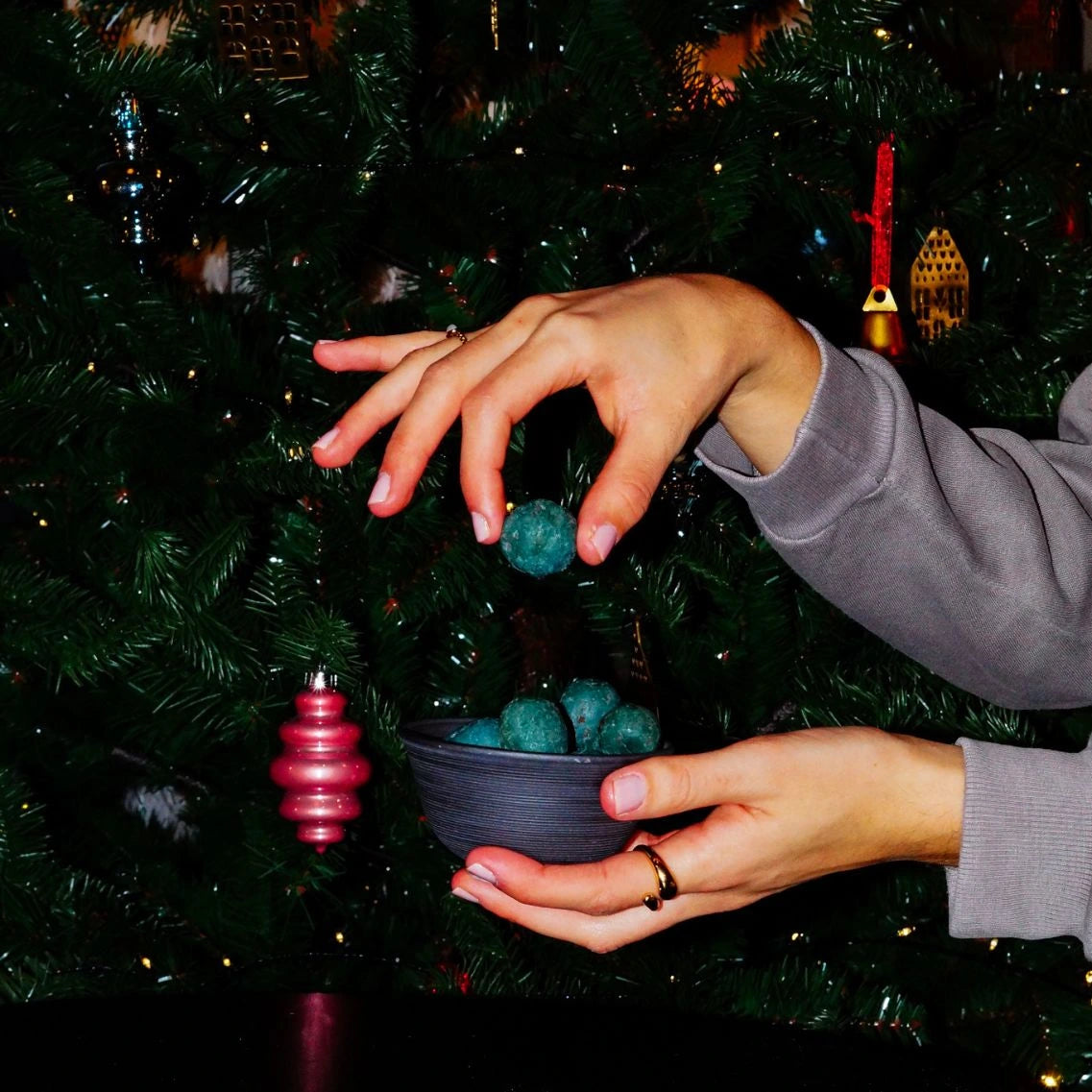 Bio Schoko Spirulina Pralinen in Schale gehalten von Hand vor Weihnachtsbaum