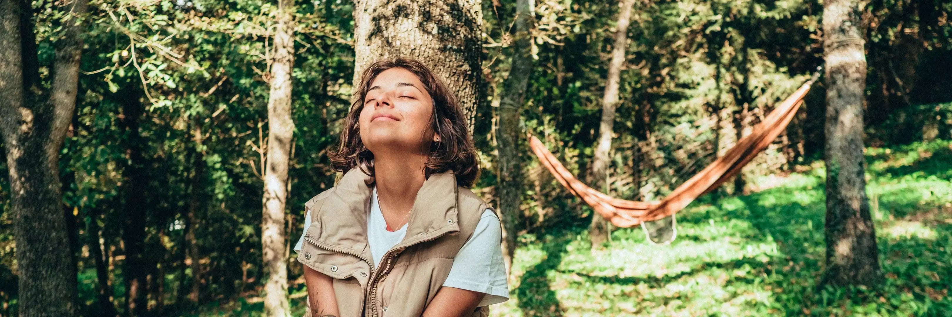 Frau in Wald mit Hängematte im Hintergrund