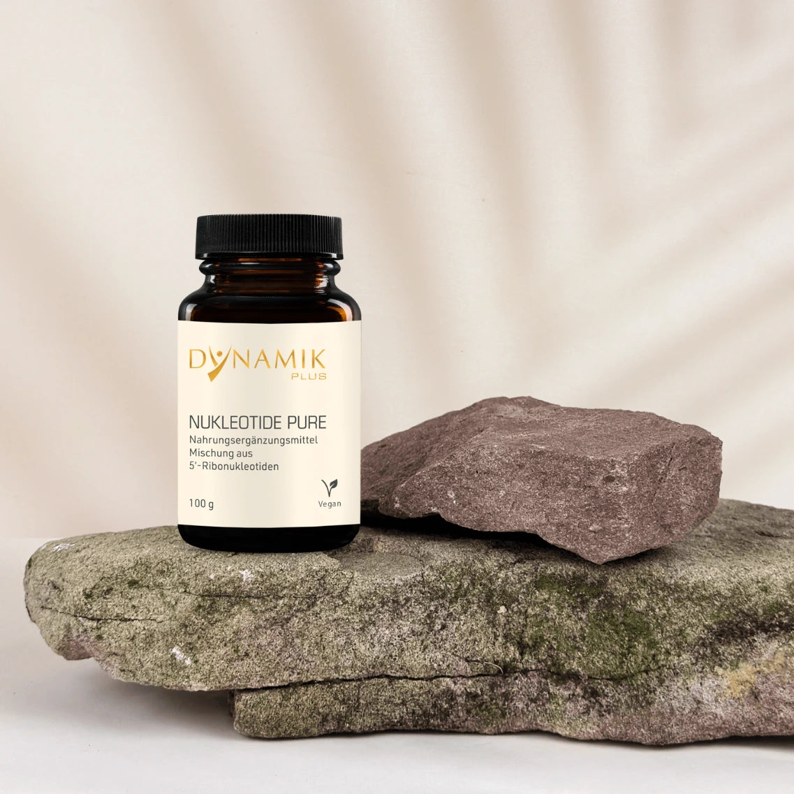 Braunes Glasbehältnis mit DYNAMIKPLUS "Nukleotide Pure" Etikett und schwarzem Drehverschluss auf Stein