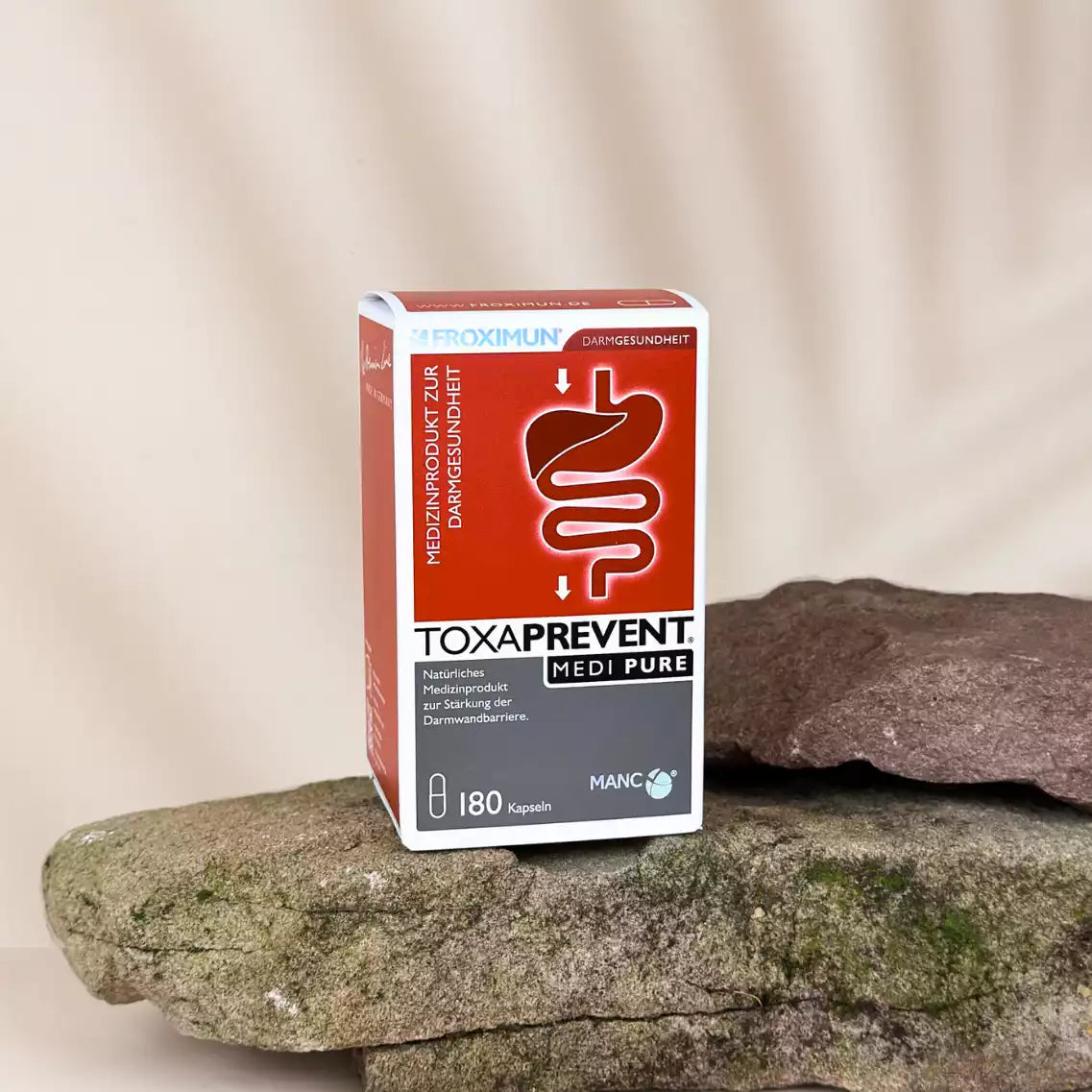 Rechteckige rot-weiße Verpackung mit "TOXAPREVENT Medi Pure 180 Kapseln" Print auf Stein