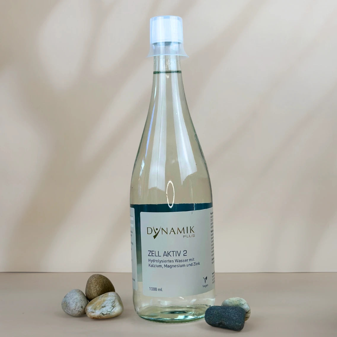 Glasflasche mit weißem Deckel, kleinem Messbecher und DynamikPlus "Zell Aktiv 2" Etikett