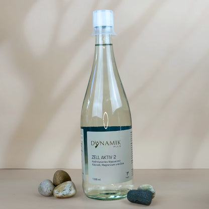Glasflasche mit weißem Deckel, kleinem Messbecher und DynamikPlus "Zell Aktiv 2" Etikett